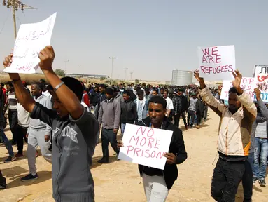 Migran Afrika berkumpul berjalan menuju Penjara Saharonim untuk melakukan aksi di gurun selatan Negev, Israel (22/2). Mereka melakukan aksi protes terkait sembilan orang dari migran Afrika yang dipenjara oleh Israel. (AFP Photo/Menahem Kahana)