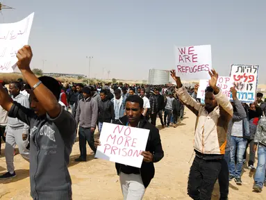 Migran Afrika berkumpul berjalan menuju Penjara Saharonim untuk melakukan aksi di gurun selatan Negev, Israel (22/2). Mereka melakukan aksi protes terkait sembilan orang dari migran Afrika yang dipenjara oleh Israel. (AFP Photo/Menahem Kahana)