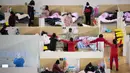Petugas medis berjalan di antara pasien dengan gejala ringan virus corona COVID-19 yang beristirahat pada malam hari di stadion olahraga yang diubah menjadi rumah sakit darurat di Wuhan, 18 Februari 2020. Jumlah korban virus corona hingga Kamis (20/2) kembali meningkat menjadi 2.120 orang. (STR/AFP)