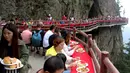 Wisatawan menyantap makanan pada acara perjamuan di sepanjang tepi tebing di Laojun Mountain provinsi Henan, China. Wisatawan menikmati berbagai suguhan makanan di jalanan selebar enam kaki yang menempel pada tebing setinggi 2.000 meter. (AFP)