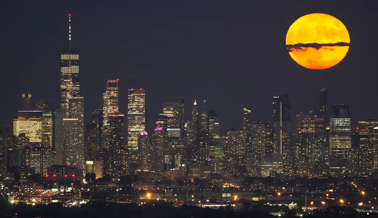 Bulan terbit menembus awan di atas cakrawala Manhattan bagian bawah dalam pemandangan dari West Orange, N.J., Selasa, 1 Agustus 2023. Supermoon pertama dari dua supermoon di bulan Agustus menghiasi langit pada hari Selasa. (AP Photo/Seth Wenig)