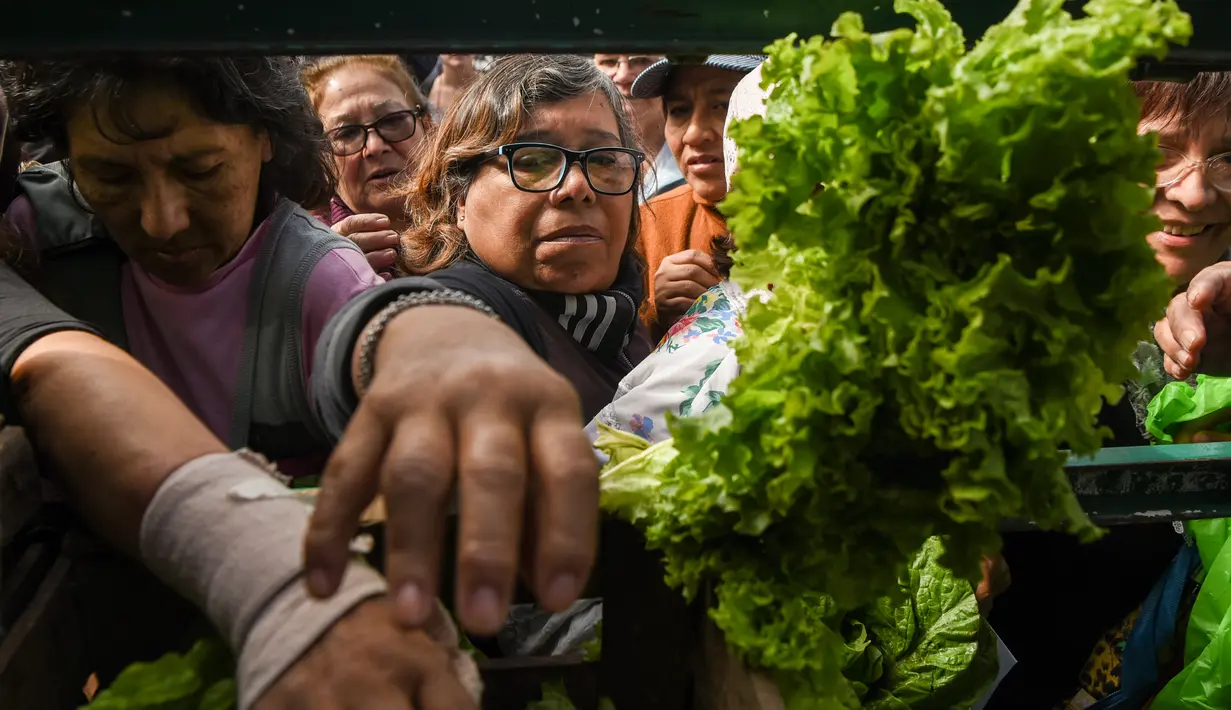 Petani membagikan sayuran secara gratis saat demonstrasi petani di alun-alun Plaza de Mayo dekat Istana Presiden Casa Rosada di Buenos Aires, Senin (24/4). (AFP FOTO / Eitan ABRAMOVICH)
