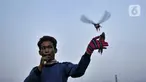 Toni membunyikan peluit saat melatih burung free fly di Jakarta, Minggu (26/7/2020). Sudah dua tahun Toni dan Sulaiman menggemari hobi bermain burung free fly yang rutin dilakukan tiap minggu untuk mengisi kegiatan saat libur kerja. (merdeka.com/Iqbal Nugroho)