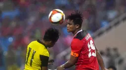 Bek Timnas Indonesia U-23, Fachruddin Wahyudi Aryanto berebut bola udara dengan penyerang Malaysia, Muhammad Syafik bin Ismail dalam pertandingan perebutan medali perunggu SEA Games 2021 di Stadion My Dinh, Minggu (22/5/2022). Indonesia ditahan imbang 1-1 dan menang 4-3 di adu penalti. (AFP/Ye Aung Thu)