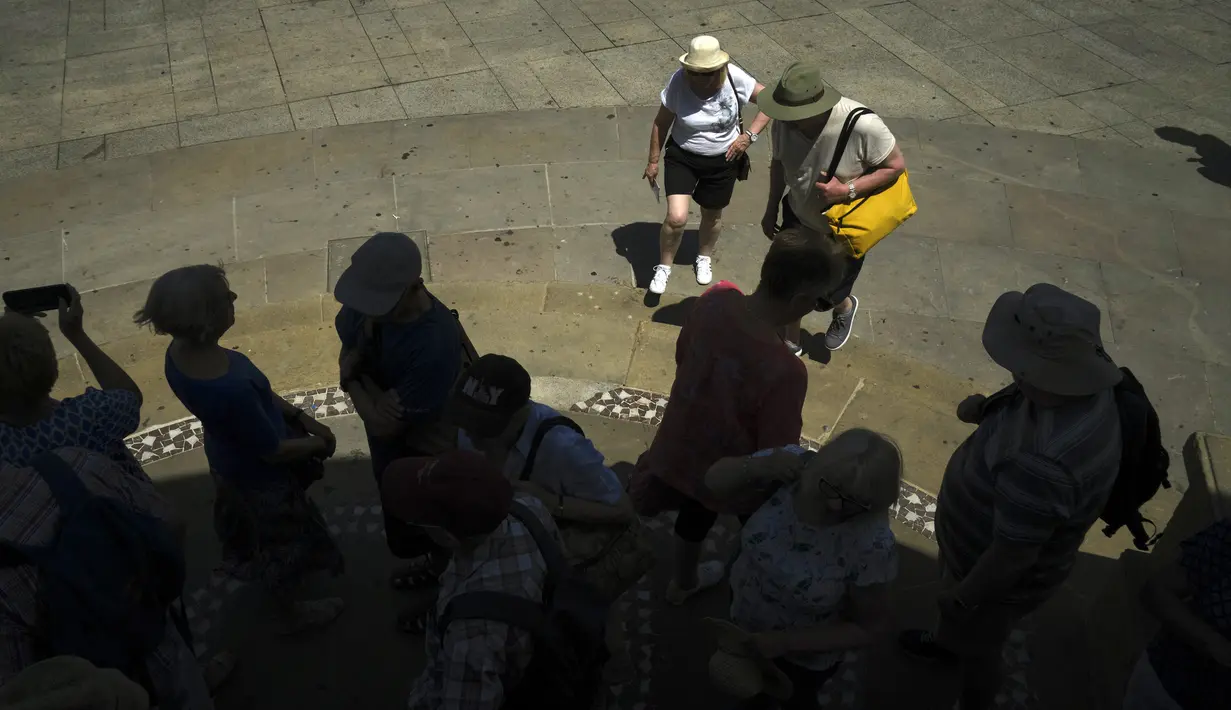 Sekelompok turis melindungi diri mereka dari sinar matahari di Alun-Alun Plaza del Castillo, Pamplona, Spanyol, 15 Juni 2022. Layanan cuaca Spanyol mengatakan massa udara panas dari Afrika Utara memicu gelombang panas besar pertama di negara itu tahun ini dengan suhu diperkirakan akan meningkat menjadi 43 derajat Celcius (109 derajat Fahrenheit) di area tertentu. (AP Photo/Alvaro Barrientos)