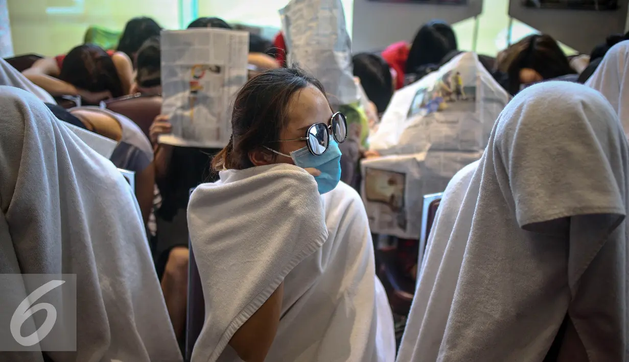 Seorang WNA menggunakan kacamata dan masker saat diamankan di Direktorat Jenderal Imigrasi, Jakarta, Minggu (1/1). Penangkapan ini didasarkan hasil penyelidikan karena puluhan wanita tersebut menyalahi aturan keimigrasian. (Liputan6.com/Faizal Fanani)