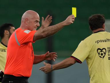 Presiden FIFA Gianni Infantino sebagai wasit menunjukkan kartu kuning kepada mantan pemain Italia Alessandro Del Piero saat pertandingan persahabatan antara pekerja dan FIFA Legends di Stadion Al Thumama di Doha, Qatar, Senin (12/12/2022). Mengikuti pertandingan terakhir di FIFA Piala Dunia Qatar 2022 Stadion Al Thumama, para tamu dan sukarelawan melihat para pekerja beberapa di antaranya memenangkan edisi terakhir Piala Pekerja, bermain berdampingan dengan beberapa nama sepak bola terbesar dalam pertarungan 60 menit.(AP Photo/ Frank Augstein)
