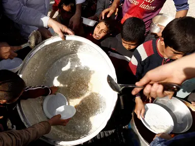 Sejumlah Warga berebut makanan saat mengungsi di kamp Khazer, Irak, (11/11). Warga terpaksa melarikan diri saat Pasukan Irak dan kelompok militan ISIS bentrok memberebutkan kota Mosul. (REUTERS/Zohra Bensemra)
