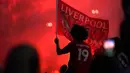 Seorang pendukung Liverpool merayakan gelar juara Liga Premier di luar Stadion Anfield, Kamis (25/6/2020). Trofi juara Liga Primer musim 2019-2020 Trofi juara Liga Primer musim 2019-2020 tersebut dimenangkan Liverpool setelah Manchester City takluk 1-2 dari Chelsea. (AP/Jon Super)