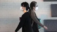 Wanita yang mengenakan masker pelindung untuk membantu mengekang penyebaran virus corona COVID-19 berjalan di Tokyo, Jepang, Jumat (16/10/2020). Tokyo mengonfirmasi lebih dari 180 kasus virus corona COVID-19 baru pada hari Jumat. (AP Photo/Eugene Hoshiko)