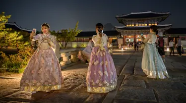 Pengunjung mengenakan gaun tradisional Korea, hanbok sambil berpose saat kunjungan malam ke Istana Gyeongbokgung di Seoul, 4 Oktober 2019. Kunjungan malam tersedia pada minggu ketiga dan keempat setiap bulan mulai dari 26 April sampai 31 Oktober, kecuali pada bulan Agustus. (Photo by Ed JONES / AFP)