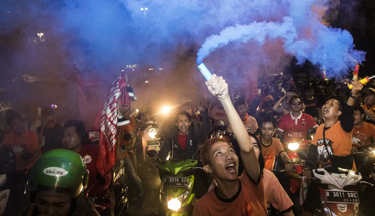 Suporter Persija Jakarta, The Jakmania, bergembira saat merayakan pesta juara Liga 1 di Bundaran Hotel Indonesia, Jakarta, Minggu (9/12). Persija unggul satu poin dari PSM Makassar di puncak klasemen. (Bola.com/Vitalis Yogi Trisna)