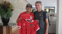 Satu di antara suporter fanatik Timnas Indonesia, Heri Istiawan, saat berfoto dengan asisten pelatih Alex Pastoor. Pria asal Banyuwangi itu sampai merogoh kocek balasan juta untuk menginap di hotel yang sama dengan Tim Garuda. (Bola.com/Alit Binawan)
