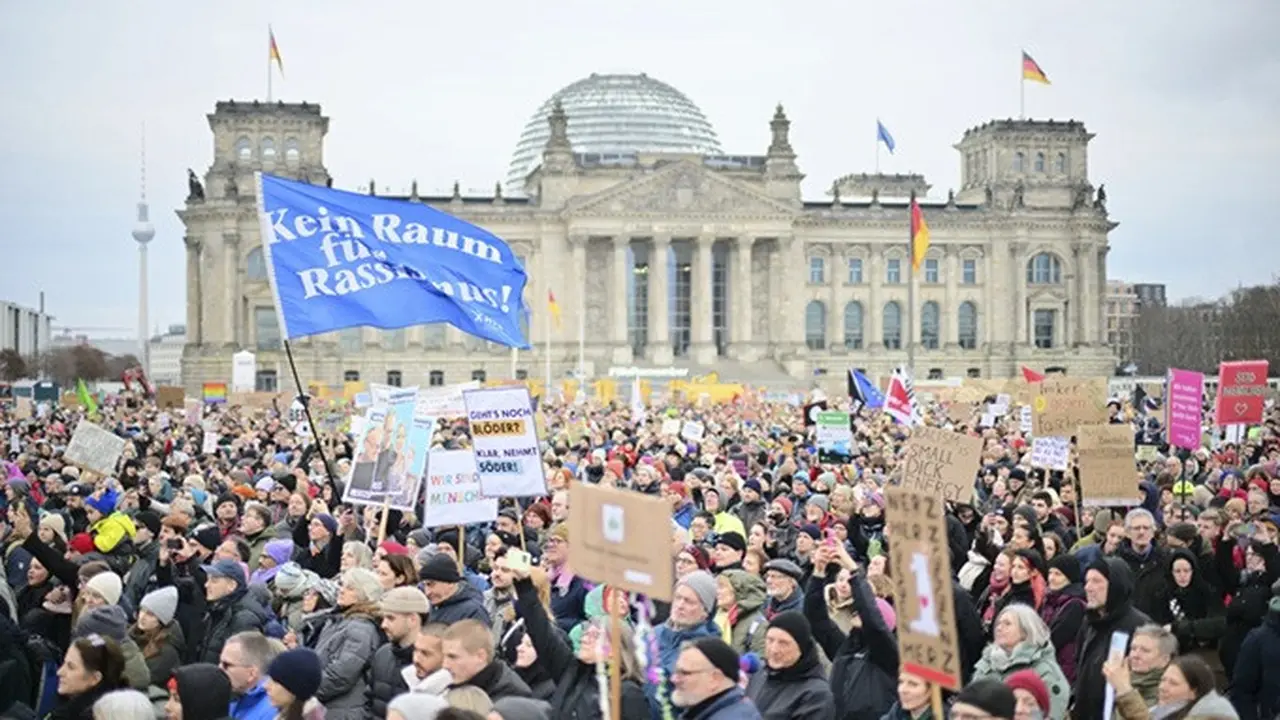 Para pengunjuk rasa memegang poster berdiri di depan Reichstag (gedung parlemen Jerman) di Berlin selama demonstrasi pada Minggu, (2/2/2025).