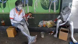 Seorang ibu bersama sang anak yang menjadi "Manusia Silver " beristirahat di salah satu sudut toko di kawasan perempatan Gaplek, Pamulang, Tangerang Selatan, Sabtu (16/1/2021). Ibu tersebut mendapat penghasilan sekitar 50 ribu per hari sebagai Manusia Silver (merdeka.com/Arie Basuki)