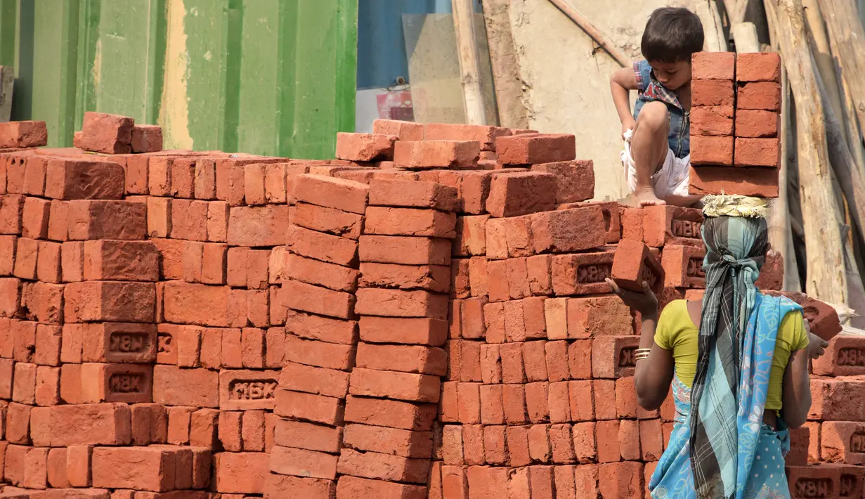 Seorang anak membantu ibunya mengangkat batu batu di sebuah bangunan New Delhi, India, Minggu (19/11). Sebagian dari mereka ada yang dipaksa ataupun terpaksa untuk membantu memenuhi kebutuhan hidup keluarganya. (DOMINIQUE FAGET)