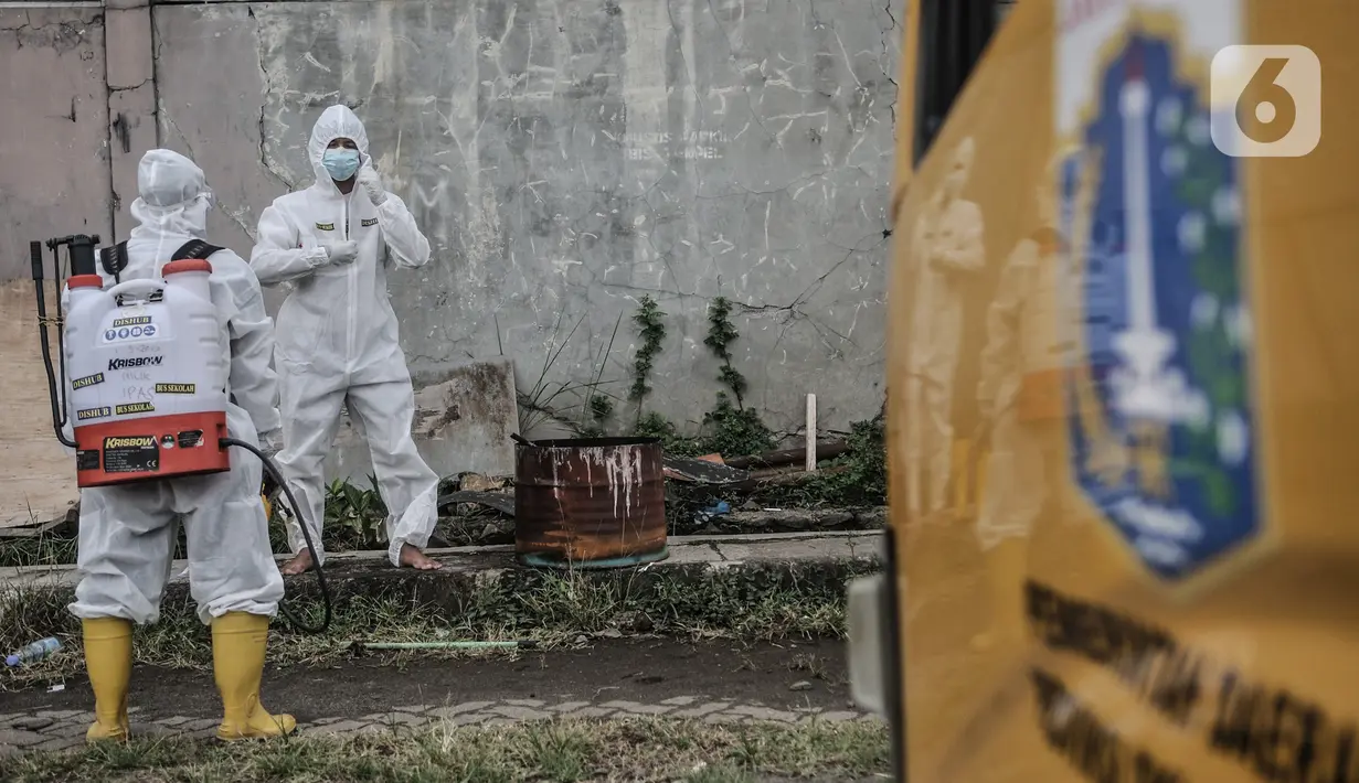 Petugas Kebersihan Bus (PKB) menyemprotkan disinfektan pada sopir bus sekolah saat proses dekontaminasi usai bertugas mengantarkan pasien terpapar Covid-19 di Pool Unit Pelayanan Angkutan Sekolah (UPAS) DKI Jakarta, Kramat Jati, Selasa (5/1/2021). (merdeka.com/Iqbal Nugroho)