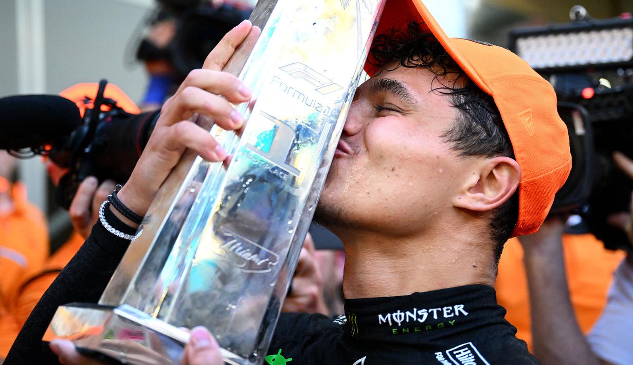 Pembalap McLaren, Lando Norris mencium trofi saat merayakan kemenangan di Formula 1 GP Miami 2024 yang berlangsung di Miami International Autodrome, Miami, Florida, Minggu (05/05/2024). (AFP/Clive Mason)
