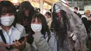 Orang-orang yang mengenakan kostum Halloween berjalan melalui distrik Shibuya yang populer di Tokyo, Minggu (31/10/2021). Daerah di sekitar Stasiun Shibuya dipadati anak-anak muda yang berdandan selama Halloween setiap tahun. (AP Photo/Koji Sasahara)