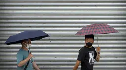 Komuter mengenakan masker dan membawa payung berjalan selama jam sibuk pagi hari pada hari hujan di Beijing, Rabu (29/6/2022). China memangkas lama karantina wajib bagi pelancong luar negeri dari 21 hari menjadi tujuh hari ditambah tiga lagi pemantauan di rumah. (AP Photo/Mark Schiefelbein)