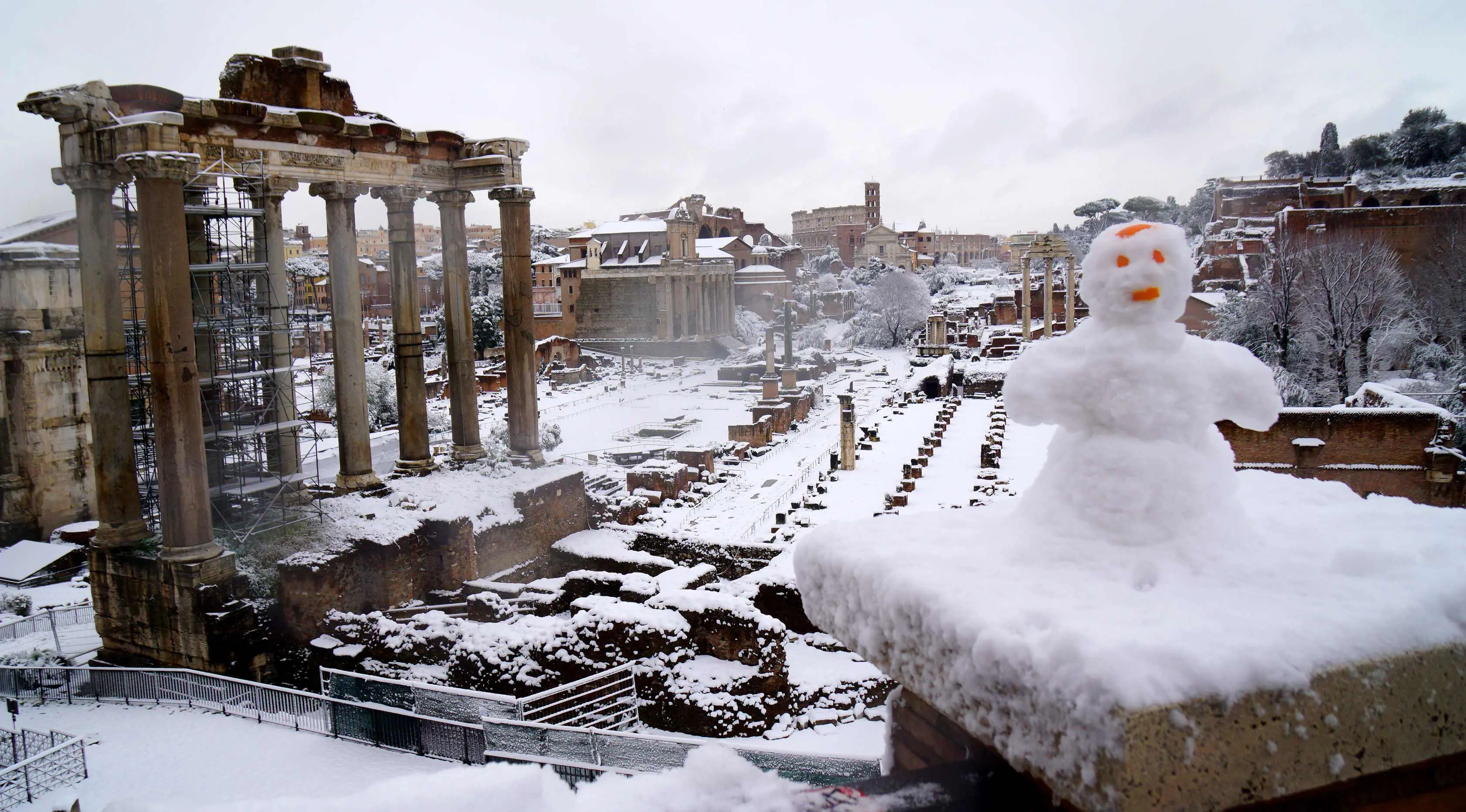 Manusia salju terlihat di dekat bangunan kuno di Roma, Italia (26/2). Badai salju yang melanda Italia menganggu transportasi dan sekolah diliburkan. (AFP Photo/Vicenzo Pinto)