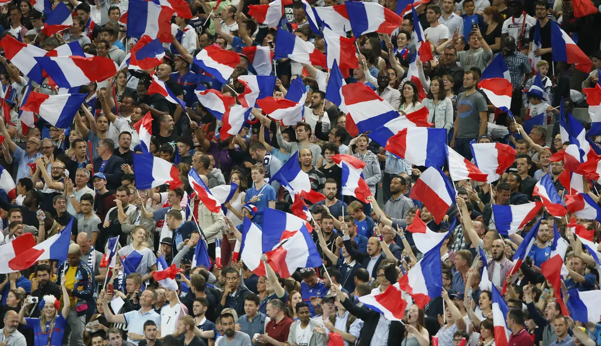 Suporter Prancis mengibarkan bendera saat timnya bertanding melawan Inggris pada laga persahabatan di Stade de France, Saint Denis, Paris, (13/6/2017).  Prancis menang 3-2. (AP/Francois Mori)
