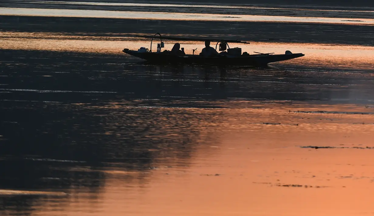 Nelayan menunggu di perahu kecil setelah memancing di Danau Dal saat matahari terbenam di Srinagar (9/9/2019). Di Sepanjang tepi Danau Dal terdapat Ghate yang merupakan tempat bersandarnya Shikara. (AFP Photo/Tauseef Mustafa)