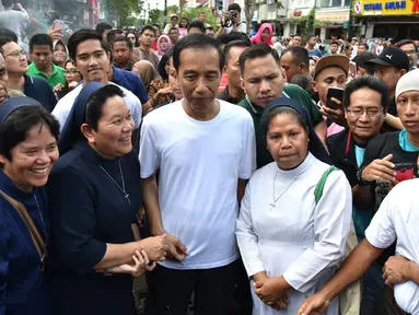 Presiden Joko Widodo (Jokowi) berfoto bersama warga saat jalan-jalan menikmati suasana jelang pergantian tahun di kawasan Malioboro, Yogyakarta, Minggu (31/12). Jokowi tampak ditemani putra bungsunya, Kaesang Pangarep. (LIputan6.com/Biro Setpres)