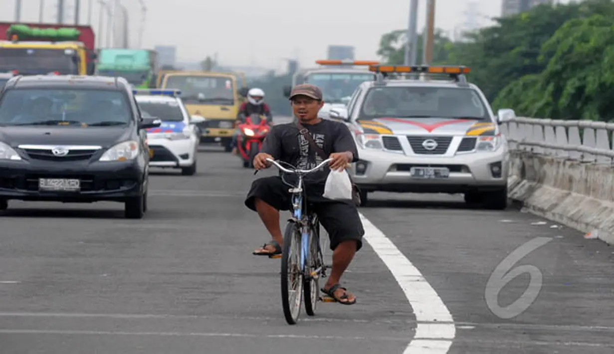Akibat banjir di kawasan Jalan Yos Sudarso, Jakarta, seorang pesepeda melintasi jalan tol Wiyoto Wiyono, Senin (10/2/2015). (Liputan6.com/Herman Zakharia)