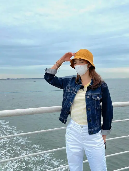 Stylish effortless, Yuki Kato memadukan yellow stripes tee dengan bucket hat warna kuning bersama jacket jeans dan white pants. (Instagram/yukikt).