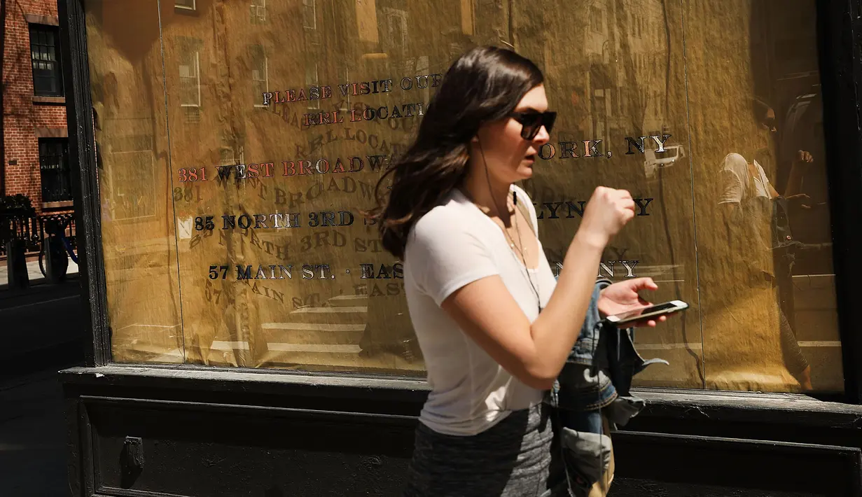 Seorang wanita berjalan di depan sebuah toko yang tutup di West Village, New York (11/4). Menurut Badan Real Estate New York (REBNY), jumlah toko tutup di New York terus meningkat. (Spencer Platt / Getty Images / AFP)