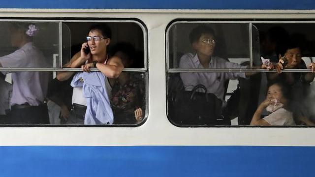 Seorang pria berbicara lewat telepon genggamnya saat ia dan penumpang lain tengah naik kereta listrik di pusat kota Pyongyang (AP)