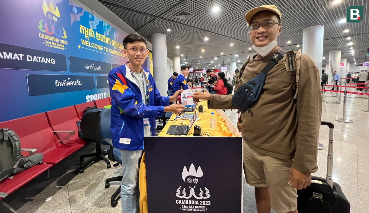 <p>Jurnalis Bola.com, Gregah Nurikhsan (kanan) memegang ID card peliputan SEA Games 2023 Kamboja yang telah diregistrasi oleh petugas di Bandara Internasional Phnom Penh, Kamboja, pada Jumat (28/4/2023). Proses registrasi berupa penempelan hologram untuk kontingen dan wartawan. (Bola.com/Abdul Aziz)</p>
