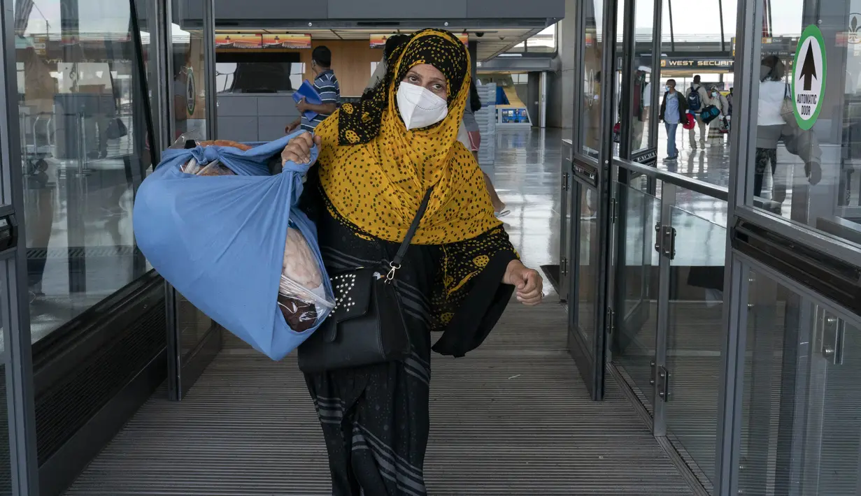Keluarga dievakuasi dari Kabul, Afghanistan, berjalan melalui terminal sebelum naik bus setelah mereka tiba di Bandara Internasional Washington Dulles, di Chantilly, Va, Rabu (25/8/2021). (AP Photo/Jose Luis Magana)