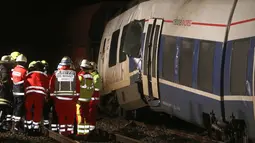 Petugas pemadam kebakaran berdiri di samping gerbong yang rusak usai terjadinya tabrakan dengan kereta lainnya di Meerbusch, Jerman, (5/12). Puluhan penumpang alami luka-luka dan tidak ada korban jiwa. (Arnulf Stoffel / dpa via AP)