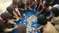 Siswa menghitung jumlah rupiah yang dihasilkan dari pengumpulan dana siswa SMP Negeri 5 Purwokerto. (Foto: Liputan6.com/Muhamad Ridlo)