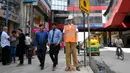 Pejalan kaki melewati manekin pria berseragam polisi lalu lintas di persimpangan jalan di Bangalore, India, Senin (16/12/2019). Polisi manekin itu diharapkan bisa mengelabui pengemudi yang akan mengiranya sebagai polisi asli sehingga mengurungkan niat melanggar lalu lintas. (Manjunath KIRAN / AFP)