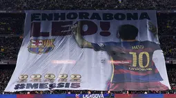 Para supporter Barcelona memberikan ucapan selamat kepada Lionel Messi usai meraih Ballon d'Or jelang laga melawan Athletic Bilbao. Tulisan di spanduk itu memiliki arti "Selamat Leo". (AFP/Josep Lago)