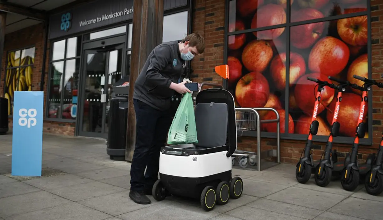 Pekerja toko Co-op memuat tas ke dalam robot otonom bernama Starship saat mengirimkan bahan makanan di Milton Keynes, Inggris, 20 September 2021. Robot Starship bertugas mengantarkan belanja dan makanan. (DANIEL LEAL-OLIVAS/AFP)