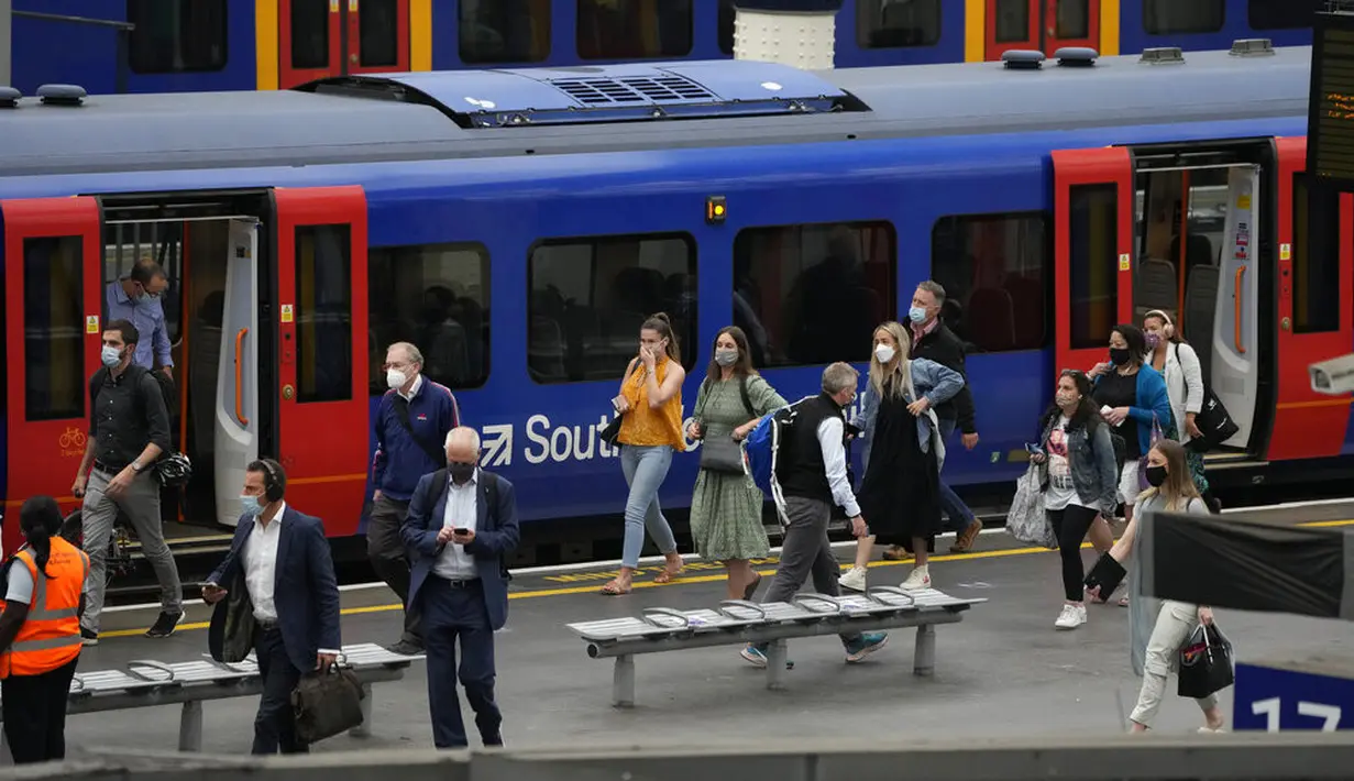 Orang-orang memakai masker setelah turun dari kereta api pada jam sibuk pagi hari di stasiun Waterloo di London, Rabu (13/7/2021). Wali Kota Sadiq Khan menekankan transportasi publik di London akan terus memberlakukan kewajiban memakai masker setelah Senin (19/7) mendatang. (AP Photo/Matt Dunham)