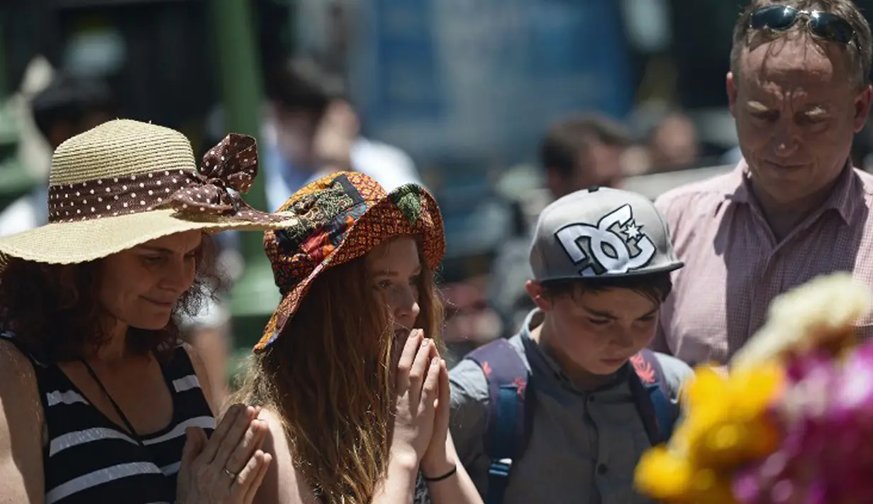 Sejumlah wisatawan ikut melakukan doa bersama di sekitar lokasi kejadian ledakan bom di Thailand), Bangkok, Rabu (19/8/2015). Peristiwa tersebut dikabarkan telah menewaskan sekitar 20 orang. (AFP Photo/Jerome Taylor)
