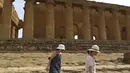 Dua wanita berjalan saat mengunjungi Lembah Kuil selama gelombang panas di dekat Agrigento, Sisilia, Italia (11/8/2021). Gelombang panas yang berkelanjutan akan berlangsung hingga akhir pekan dengan suhu diperkirakan mencapai lebih dari 40 derajat Celcius di banyak bagian dari Italia. (AP Photo/Salv