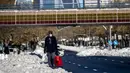 Seorang pria melewati salju di sepanjang Paseo Castellana di Madrid, Senin (11/1/2021). Ibu kota Spanyol itu berusaha bangkit kembali setelah menghadapi badai salju terburuk dalam 50 tahun terakhir yang melumpuhkan sebagian besar wilayah Spanyol tengah selama akhir pekan. (AP Photo/Manu Fernandez)