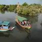 Perahu wisata melintasi kerumunan wisatawan yang berjalan di atas Jembatan Cinta di Wisata Mangrove, Tarumajaya, Bekasi, Minggu (30/12). Wisata tersebut berbatasan langsung dengan kawasan Marunda Jakarta Utara. (merdeka.com/Arie Basuki)