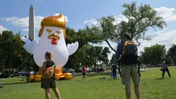 Wisatawan mengamati balon raksasa berbentuk ayam yang diletakkan di sebuah taman di belakang Gedung Putih, Washington DC, 9 Agustus 2017. Balon itu sebagai bentuk protes terhadap kepemimpinan Donald Trump yang dinilai tidak tegas. (Mandel NGAN/AFP)
