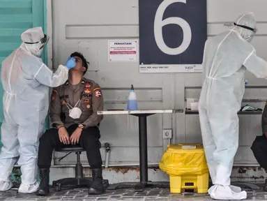 Petugas kesehatan melakukan swab test PCR pada personel polisi di Laboratoriun GSI Cilandak, Jakarta Selatan, Rabu (18/8/2021). Pemerintah melalui Kementerian Kesehatan resmi menetapkan tarif tertinggi pemeriksaan Real Time Polymerase Chain Reaction (RT-PCR). (merdeka.com/Iqbal S. Nugroho)