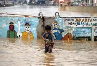 Seorang anak bermain air saat banjir menggenangi Jalan Jatinegara Barat, Jakarta Timur, Selasa (6/2). Deras dan tingginya debit air di Kali Ciliwung membuat Jalan Jatinegara Barat terputus. (Liputan6.com/Arya Manggala)