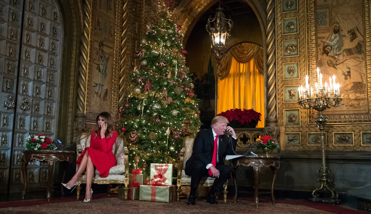 Presiden AS Donald Trump dan istrinya berbicara di telepon dengan anak-anak saat mereka mengikuti NORAD Tracks Santa di Palm Beach, AS (24/12). Biasanya sukarelawan yang bekerja diambil dari personel militer NORAD dan warga sipil.(AP Photo/Carolyn Kaster)