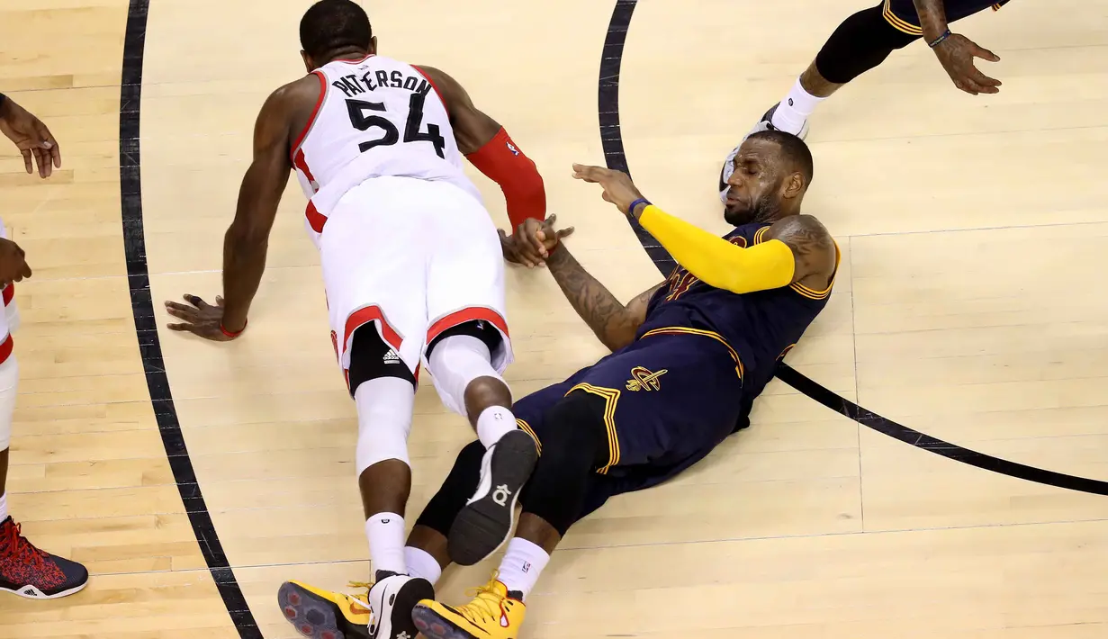 Pemain Raptors, Patrick Patterson #54 terjatuh bersama pemain Cavaliers, LeBron James #23  pada final Wilayah Timur NBA Playoffs 2016 di Air Canada Centrer, Selasa (24/5/2016), Toronto, Ontario, Canada. (Tom Szczerbowski/Getty Images/AFP)