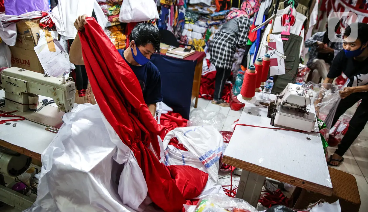 Pekerja menjahit bendera merah putih di kiosnya, kawasan Pasar Senen, Jakarta, Rabu (5/8/2020). Menjelang peringatan HUT ke-75 Kemerdekaan RI, sejumlah pedagang mengaku penjualan pernak-pernik bendera merah putih menurun 50 persen dibanding tahun lalu akibat COVID-19. (Liputan6.com/Faizal Fanani)